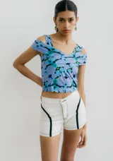 Top de jersey ajustado con estampado abstracto en tonos azules, morados y negros. Presenta un diseño cruzado en el frente que crea un escote en V y tirantes que caen sobre los hombros.