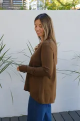 Sweater de punto color chocolate, con cuello redondo, manga larga y puños acanalados. Presenta un corte holgado con ruedo asimétrico.