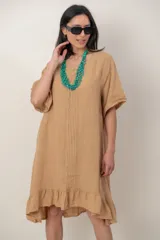Vestido midi de lino color beige, con mangas cortas, cuello redondo, alforzas verticales en el pecho y detalle de volados en el ruedo.