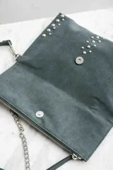 Cartera bandolera negra con tachas plateadas, confeccionada en gamuza vegana.