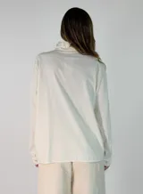 Camisa de pana color marrón oscuro, con cuello mao y cierre frontal de botones. Presenta un diseño de manga larga con puños clásicos y corte recto.