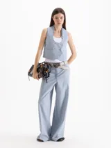 Pantalón de vestir tiro alto color celeste, de corte wide leg y largo hasta el suelo, con bolsillos delanteros decorados con volados tableados y bolsillos ojal en la espalda.