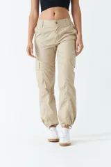 Pantalón cargo color beige de tiro medio, con bolsillos laterales tipo cargo y puños ajustables en los tobillos.