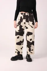 Pantalón jean de corte recto con estampado de manchas de vaca en blanco y negro.