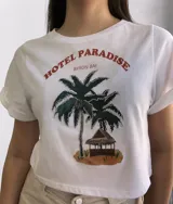 Remera corta negra con mangas cortas con dobladillo y estampado de palmera con luces y cabaña en la playa.