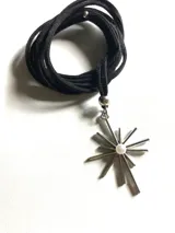 Collar con lazo de cuero negro y dije de acero quirúrgico en forma de estrella de puntas alargadas con una perla central.