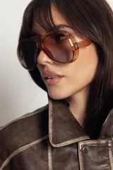 Lentes de sol estilo aviador con armazón de policarbonato en tono ámbar translúcido y cristales degradados en tonos marrones. Cuentan con protección UV400.