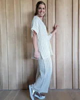 Pantalón de punto calado color crudo, de corte palazzo y cintura elástica.