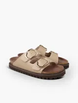 Sandalia plana de cuero taupe con textura, dos tiras ajustables con hebillas metálicas doradas hexagonales, plantilla anatómica y suela marrón de goma con plataforma dentada.