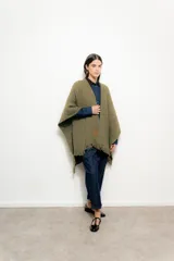 Ruana color verde oliva de tejido grueso con flecos en el borde inferior.