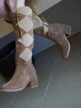 Botas de caña alta con diseño geométrico en tonos turquesa, magenta y gris. Confeccionadas en gamuza y cuero, con taco bajo y cierre lateral.