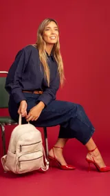 Mochila color marrón claro de símil cuero con bolsillos frontales con cierre. Tiene asa de mano rígida y correas regulables.