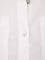 Camisa de manga corta color beige, confeccionada en mezcla de algodón y lino, con cuello camisero, cierre frontal de botones y dos bolsillos aplicados en el pecho.
