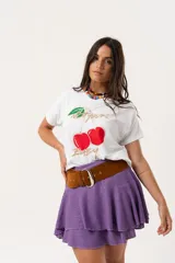 Remera blanca de algodón y elastano, con cuello redondo y mangas cortas. Estampado frontal con cerezas y texto en dorado.