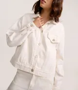 Campera trucker confeccionada en sarga de algodón color blanco, con cuello tradicional, cierre frontal de botones metálicos, bolsillos frontales con solapa y costuras reforzadas.