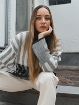 Sweater tejido a rayas horizontales color beige, marrón y negro, de cuello alto y corte holgado.