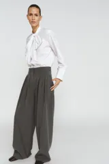 Pantalón de tiro medio con pinzas frontales, confeccionado en tejido con viscosa. Presenta cintura con trabillas, bolsillos laterales y cierre frontal con cremallera, botón y ganchos metálicos.