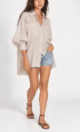 Camisa oversize de lino, color blanco, de corte asimétrico con cuello camisero, bolsillos plaque al frente y mangas abullonadas.