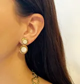 Caravanas artesanales de bronce con dos piedras naturales engarzadas en disposición vertical, una de color azul y otra gris. Presentan un acabado rústico con detalles circulares y cierre de presión.