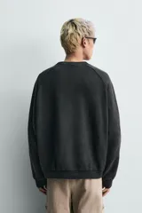 Sudadera de corte relaxed fit confeccionada en tejido de algodón con interior de rizo. Presenta cuello redondo, manga larga y acabados en rib, con un acabado de efecto lavado que le otorga una apariencia única.