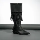 Bota tejana de caña alta color negro, confeccionada 100% en cuero vacuno. Presenta taco de madera foliado en cuero, cierre YKK del lado interior y flecos colocados a mano en la caña.