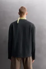 Sudadera de ajuste regular, color verde oliva, con cuello redondo y manga larga. Presenta una textura irregular en el tejido, similar al borreguito o bouclé.