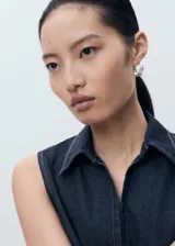 Top sin mangas estilo chaleco confeccionado en tejido de algodón y lino, con cuello solapa, cierre frontal con cremallera y costuras en contraste.