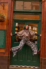 Camisa de manga larga con estampado a cuadros en tonos beige, marrón y azul. Presenta volados en las mangas, botones a la vista, puños elásticos y tiritas ajustables en el dobladillo para entallar.