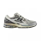 Championes urbanos New Balance modelo 1906, con diseño técnico de estilo retro. Presentan una combinación de malla transpirable y paneles sintéticos en tonos gris, blanco y detalles en azul. Incorporan entresuela con tecnología de amortiguación y suela de goma resistente.