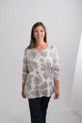 Sweter de punto amplio con escote en V y manga larga. Presenta un estampado de flores estilo acuarela en tonos verdes sobre fondo beige.