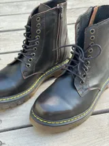 Bota corta de cuero color chocolate, con cordones amarillos y cierre lateral.