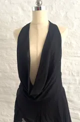 Vestido corto negro con escote halter y cuello drapeado. Presenta un diseño ajustado en la parte superior y falda con volados en la parte inferior.