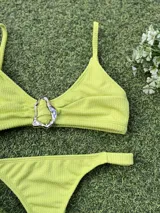 Conjunto de bikini color lima con textura, compuesto por un top triangular con detalle de hebilla metálica plateada en el centro y bombacha colaless.