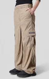 Pantalón cargo de corderoy color arcilla, de calce regular y diseño holgado. Cuenta con seis bolsillos, incluyendo bolsillos laterales tipo cargo con solapa y etiqueta decorativa.