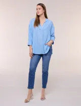 Blusa de silueta holgada a rayas verdes y blancas, confeccionada en tela liviana con textura arrugada. Presenta cuello en V profundo con botones frontales, mangas 3/4 de hombro caído y ruedo asimétrico con aberturas laterales.