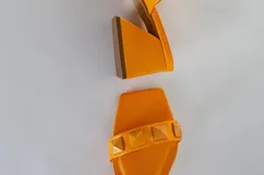 Sandalias rojas de tacón con dos tiras sobre el empeine adornadas con tachas piramidales. El tacón es ancho y de altura media.