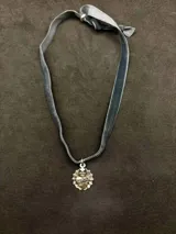 Gargantilla de cinta de terciopelo gris con dije de medalla del Sagrado Corazón en aleación bañada en plata.