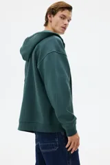 Campera con capucha de felpa de peso medio con interior cepillado suave. Presenta hombros caídos, cierre frontal, bolsillos tipo canguro y cordones ajustables en la capucha. Los puños y el bajo están terminados en punto acanalado.