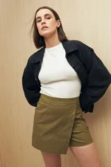 Short pollera color marrón de tiro alto, confeccionado en algodón. Presenta solapa frontal que simula una falda y bolsillos delanteros.