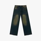 Pantalón de jean con corte baggy, color azul oscuro con efecto de lavado desgastado en tono amarillento. Presenta costuras en contraste, diseño de cinco bolsillos y terminación de ruedo deshilachado.