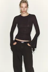 Camiseta de cuello redondo y manga larga, confeccionada en tejido rib con mezcla de lyocell. Presenta un diseño ajustado con terminación de volantes en los puños y bajo recto.