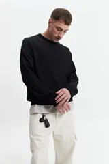 Buzo de punto oversize color negro, con escote redondo y puños.