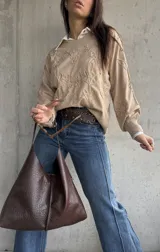 Sweater de punto color beige con diseño bordado en relieve de flores y hojas. Presenta cuello redondo, mangas largas con puños acanalados y un corte holgado.