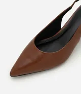 Zapato tipo slingback de punta fina en color marrón, con tira trasera ajustable y tacón bajo tipo kitten heel.