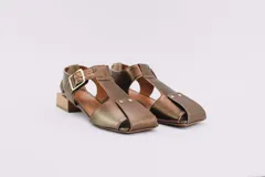 Sandalias de cuero color bronce, con diseño de punta cuadrada, taco cuadrado símil madera y tira ajustable con hebilla en el tobillo.