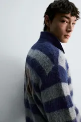 Polo de punto cepillado con diseño de rayas horizontales en azul marino y gris. Presenta cuello solapa con abertura frontal, manga larga y texto bordado en el pecho. Acabados en rib en puños y ruedo.