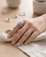 Anillo ancho de plata con diseño texturizado en relieve y pequeñas piedras circulares de rubí incrustadas.