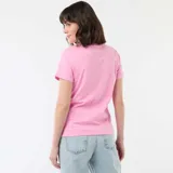Remera rosa de manga corta y cuello redondo, con estampa frontal en color bordó que incluye texto y el dibujo de un sol.