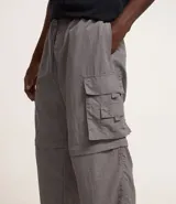 Pantalón cargo negro de corte recto con bolsillos laterales tipo cargo. Presenta cintura elástica con cordón de ajuste y sistema de tiradores en la parte inferior para regular el largo, permitiendo convertirlo en bermuda.
