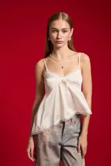 Musculosa de satén color blanco, con breteles finos regulables, escote en V decorado con detalles de encaje y diseño fluido.